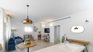 A modern kitchen with a large island, a dining area with a round table, and a living room with a sofa and chairs. - Tlv Center by Tlv2rent (Tel Aviv)