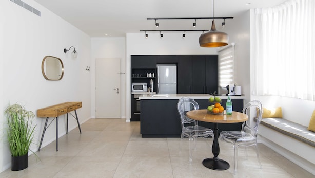 A modern kitchen with a central island, clear chairs, and a dining table with fruit. - Tlv Center by Tlv2rent (Tel Aviv)