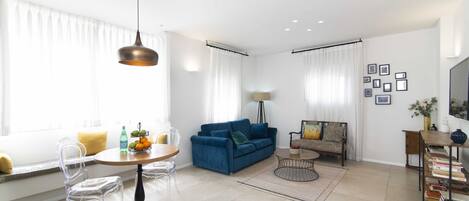 Una sala de estar moderna con un sofá azul, una mesa de centro redonda y una estantería.