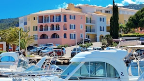 A marina with boats docked, a building with balconies, and a clear blue sky.