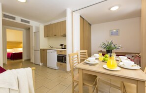 Una cocina moderna con armarios de madera, lavavajillas y un comedor con mesa lista para el desayuno.