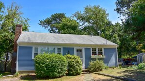 A single-story house with a grey roof, white trim, and a number '14' on the door. - Cozy 2 bedroom cottage less than a mile to the beach (Dennis Port)
