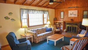A cozy living room with a plaid sofa, a blue recliner, a wooden rocking chair, a coffee table, and a fireplace. - Cozy 2 bedroom cottage less than a mile to the beach (Dennis Port)