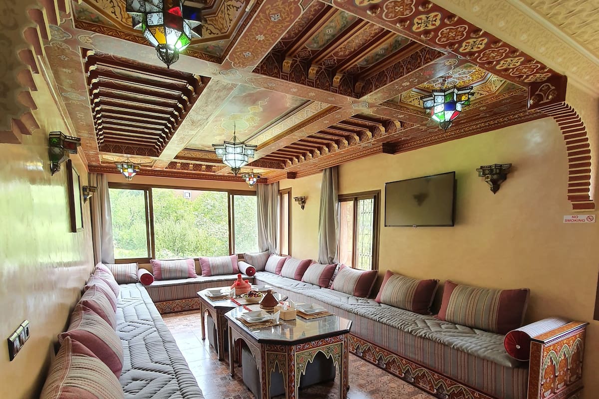 Um interior tradicional com mobiliário de madeira ricamente detalhado, piso padronizado e elementos decorativos no teto.