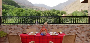 Mesa con platos y vasos, con vistas a un paisaje montañoso.