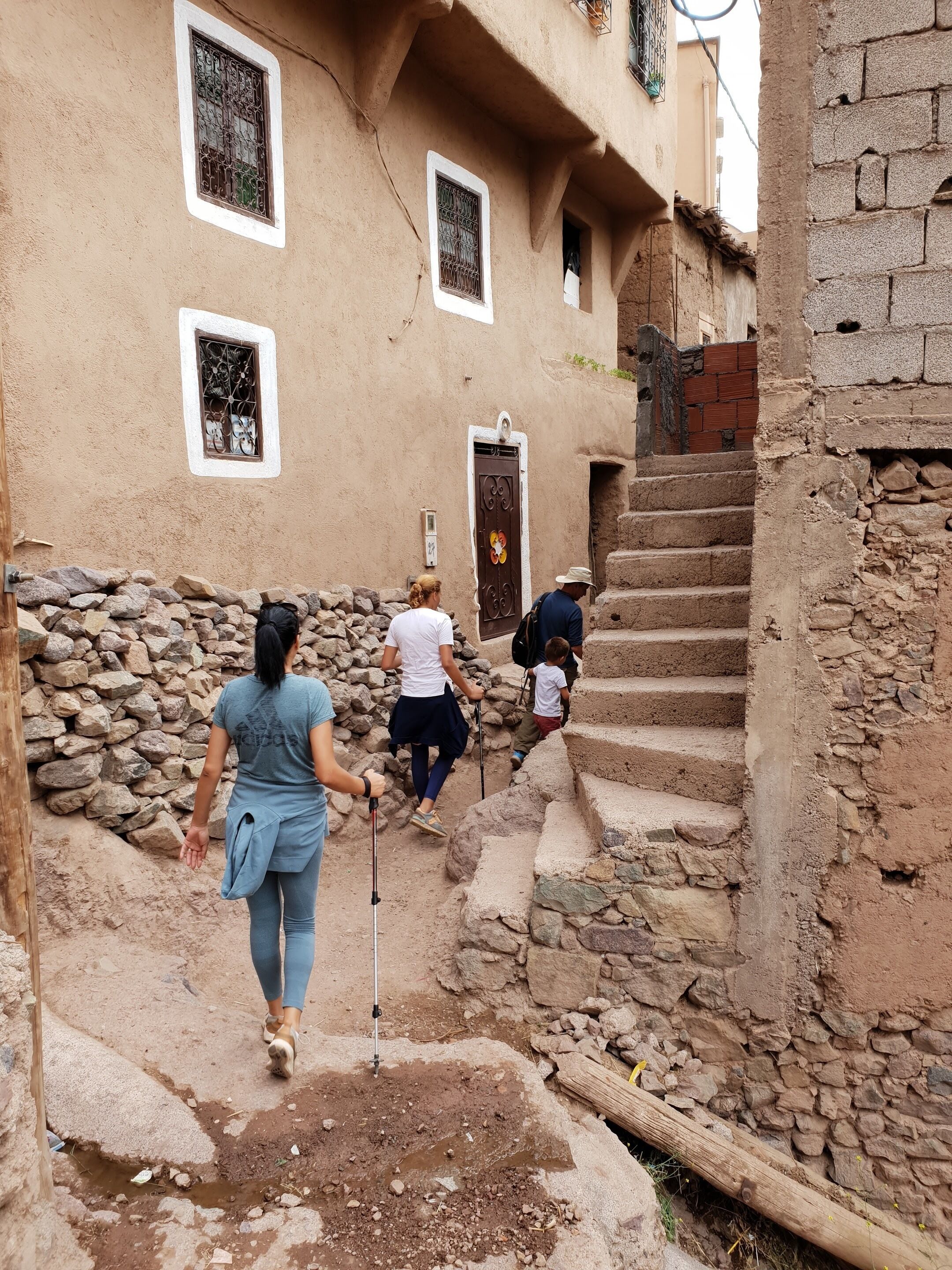 Un estrecho callejón empedrado con un edificio rústico que presenta una puerta de madera y un ventanal pequeño.