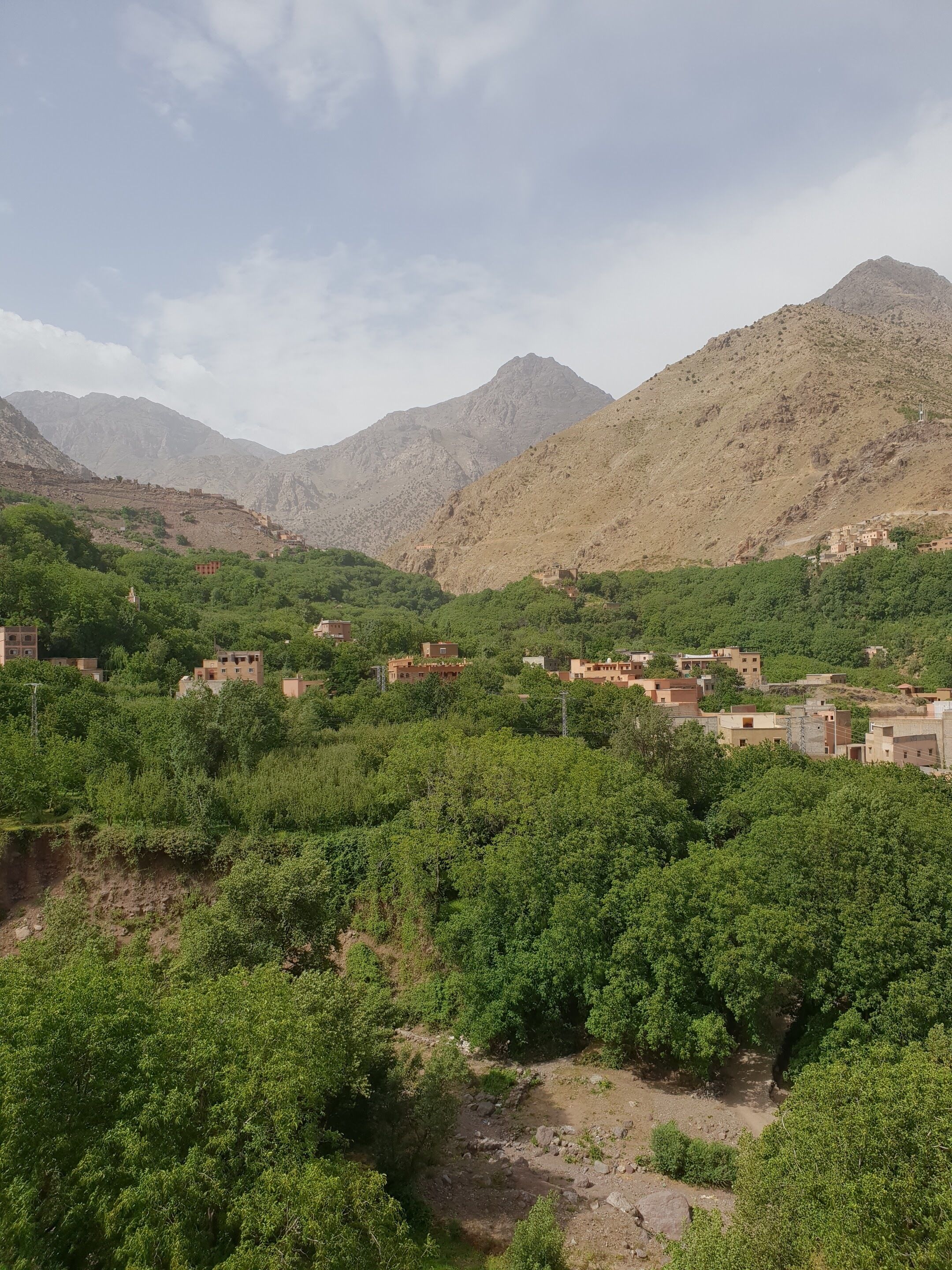 Un paysage montagneux avec un village niché au milieu de collines verdoyantes et d’un terrain rocheux.