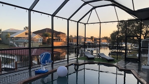 An indoor swimming pool with a clear view of the surrounding neighborhood, including houses and a body of water. - Villa Oasis, w/Heated & Covered Pool, Pool Table, Boat Dock, Gym and much more. (Apollo Beach)