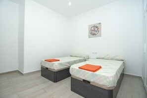 Una habitación pequeña y limpia con dos camas, cada una con una almohada y una toalla naranja.
