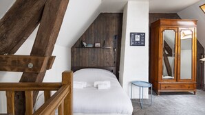 Quarto com estrutura de cama de madeira, guarda-roupa de madeira e uma pequena mesa.