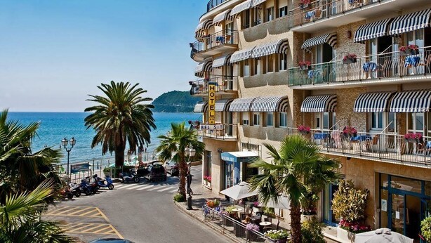 A hotel with multiple balconies, outdoor seating, and a view of the sea. - Hotel Bel Sit (Alassio)
