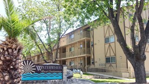 A multi-story building with a sign for Waterwheel Resort Condominiums. - Riverside Retreat | Riverfront | King Bed | Two Pools (New Braunfels)