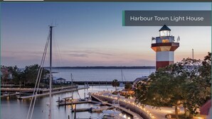 A waterfront marina with boats docked, a lighthouse, and a well-lit pathway.