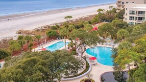 A resort with a large pool, a beach view, and a building with balconies.