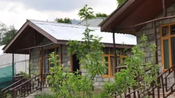 A stone building with a metal roof and wooden windows. - Natures Outpost Camps (Kullu)