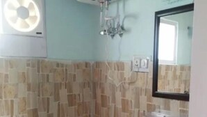 A small bathroom with a toilet, sink, and a water heater mounted on the wall. - Natures Outpost Camps (Kullu)