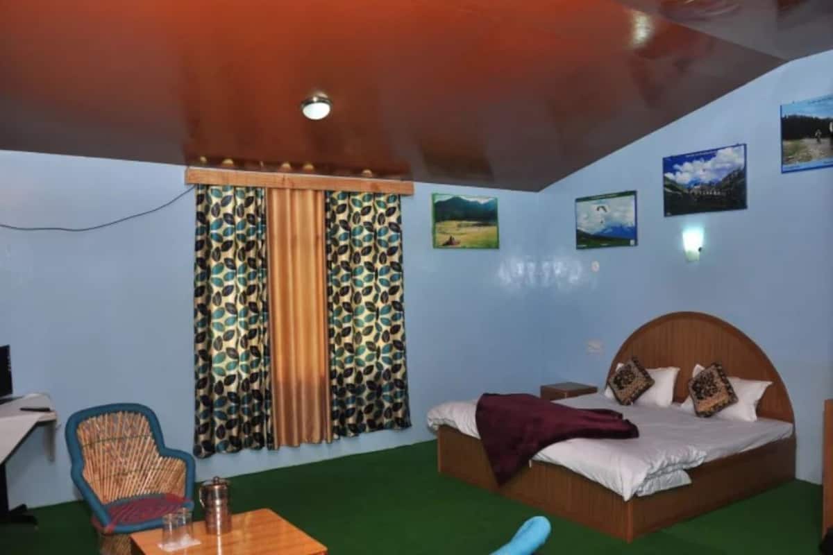 A bedroom with a bed, a desk, a chair, and curtains.