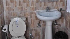 A bathroom with a toilet, sink, and a hand dryer. - Natures Outpost Camps (Kullu)