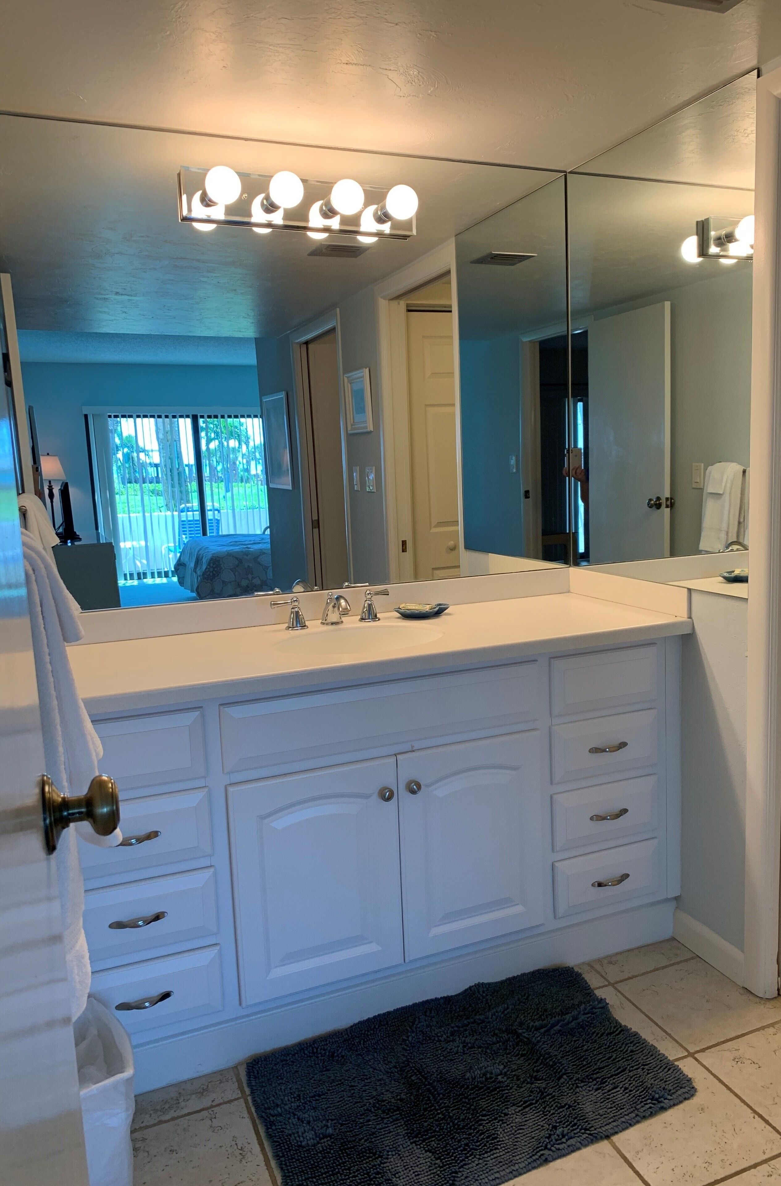 A bathroom with a white vanity, a large mirror, and a lighted vanity area.