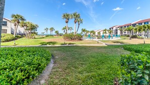 A resort with a well-maintained lawn, palm trees, and a clear view of the ocean. - 2 Bedroom, 2 Bathroom, Ground Floor, Pool View (Sarasota)