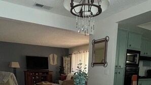 A dining area with a wooden table, cushioned benches, a vase with greenery, and a chandelier.