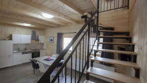 Un intérieur en bois comprenant une cuisine, un coin repas et un escalier.