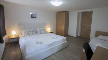 A hotel room with a large bed, bedside tables with lamps, a wooden wardrobe, and a door.
