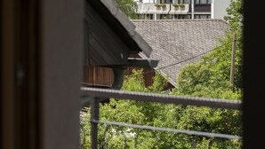 Une vue depuis un balcon, avec une table et une chaise, donnant sur un paysage montagneux où l’on aperçoit, sur une colline, une structure qui ressemble à un château.
