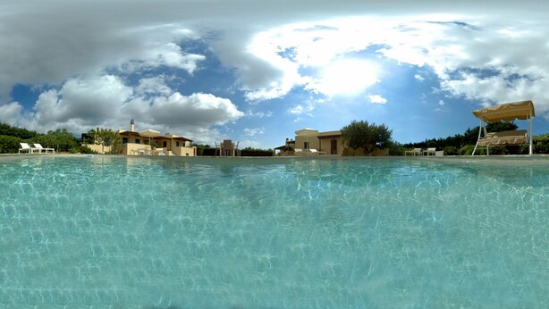 A clear swimming pool with a view of buildings and a cloudy sky. - Naxos Cottage - Cottage 1 (Naxos)