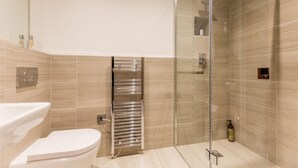 A modern bathroom with a glass shower enclosure, a white toilet, and a towel rack. - Cocoa Suites 5 - sleeps 2 guests  in studio apartment (York)