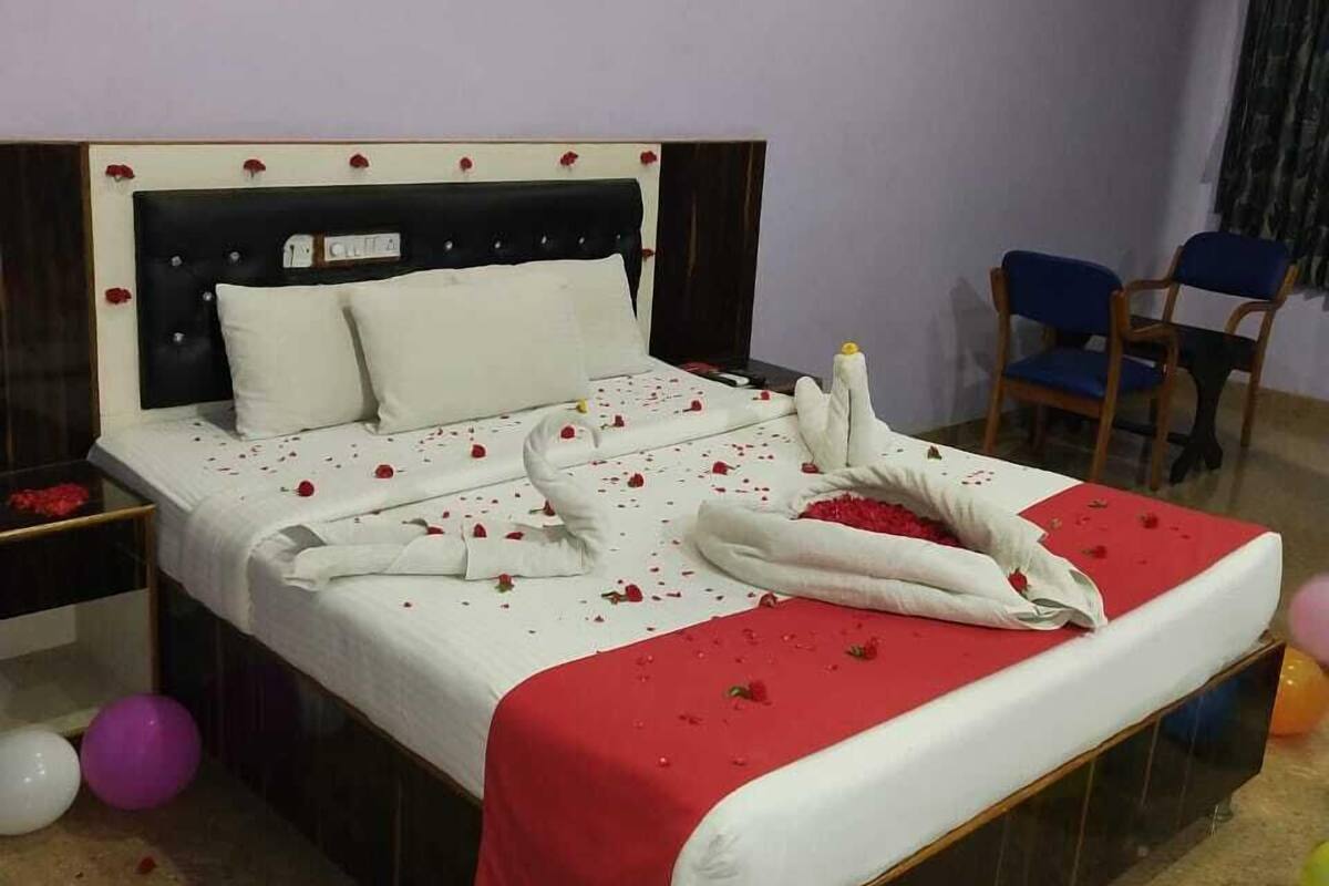 A bedroom with a bed, a nightstand, a chair, and balloons.