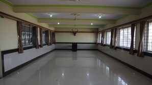 A spacious, well-lit room with a polished floor, large windows with curtains, and a ceiling fan. - Elite Inn (Bengaluru)