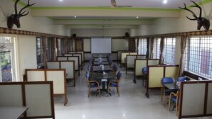 A conference room with a long table, blue chairs, and partition walls. - Elite Inn (Bengaluru)