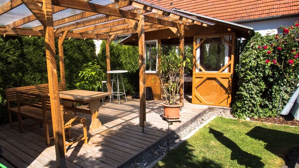 A wooden deck with a pergola, a table, and a bench. - Haus Steinberg (DTV 3 Sterne) - Herbi's holiday apartment - Ground floor   (Burladingen)