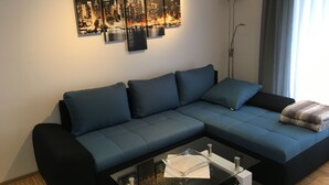 A modern living room with a sectional sofa, a glass coffee table, and a cityscape artwork on the wall. - Haus Steinberg (DTV 3 Sterne) - Herbi's holiday apartment - Ground floor   (Burladingen)