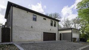 A two-story building with a garage and a covered area, surrounded by a paved driveway and a gravel area. - The Perfect Hideaway - Plan Your 30 Day Escape (Nashville)