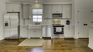 A modern kitchen with white cabinetry, stainless steel appliances, and a wooden floor. - The Perfect Hideaway - Plan Your 30 Day Escape (Nashville)