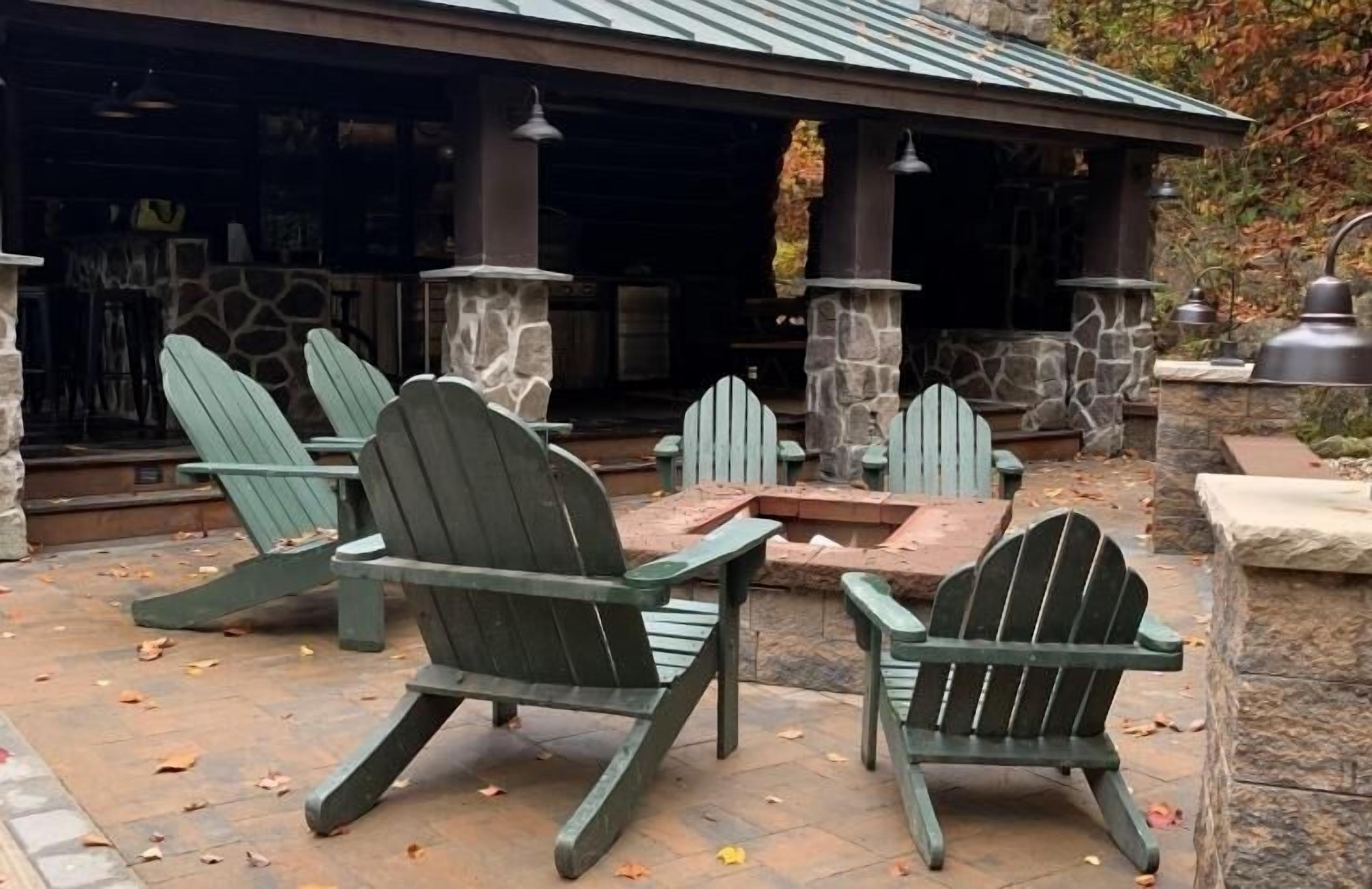 Un patio con sillas Adirondack y una chimenea de piedra.