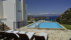 A pool area with lounge chairs, a staircase, and a view of the sea and mountains. - Beautiful seaview villa with private sea water pool (Agios Nikolaos)