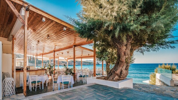 An outdoor dining area with tables and chairs, a wooden pergola, and a view of the sea. - Beautiful seaview villa with private sea water pool (Agios Nikolaos)