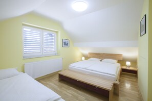 A bedroom with a bed, bedside tables, a bench, a window with blinds, a radiator, and a ceiling light. - Apartment Karolina (Bled)