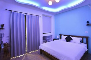 A bedroom with a bed, curtains, a nightstand, a lamp, and a shelf.