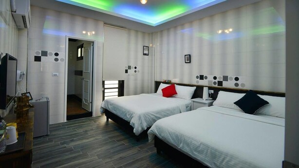 Una habitación de hotel con dos camas, una lámpara de techo y una mesita con lámpara.
