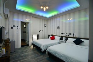 A hotel room with two beds, a ceiling light, and a small table with a lamp. - And B&B (Hengchun)