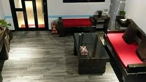 Un salón moderno con una pared de acento de piedra, un sofá rojo, una mesa de centro de madera y una mesa de centro con superficie de vidrio.