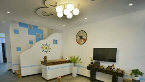 Un área de recepción con un mostrador de madera, un reloj, un televisor y una planta.