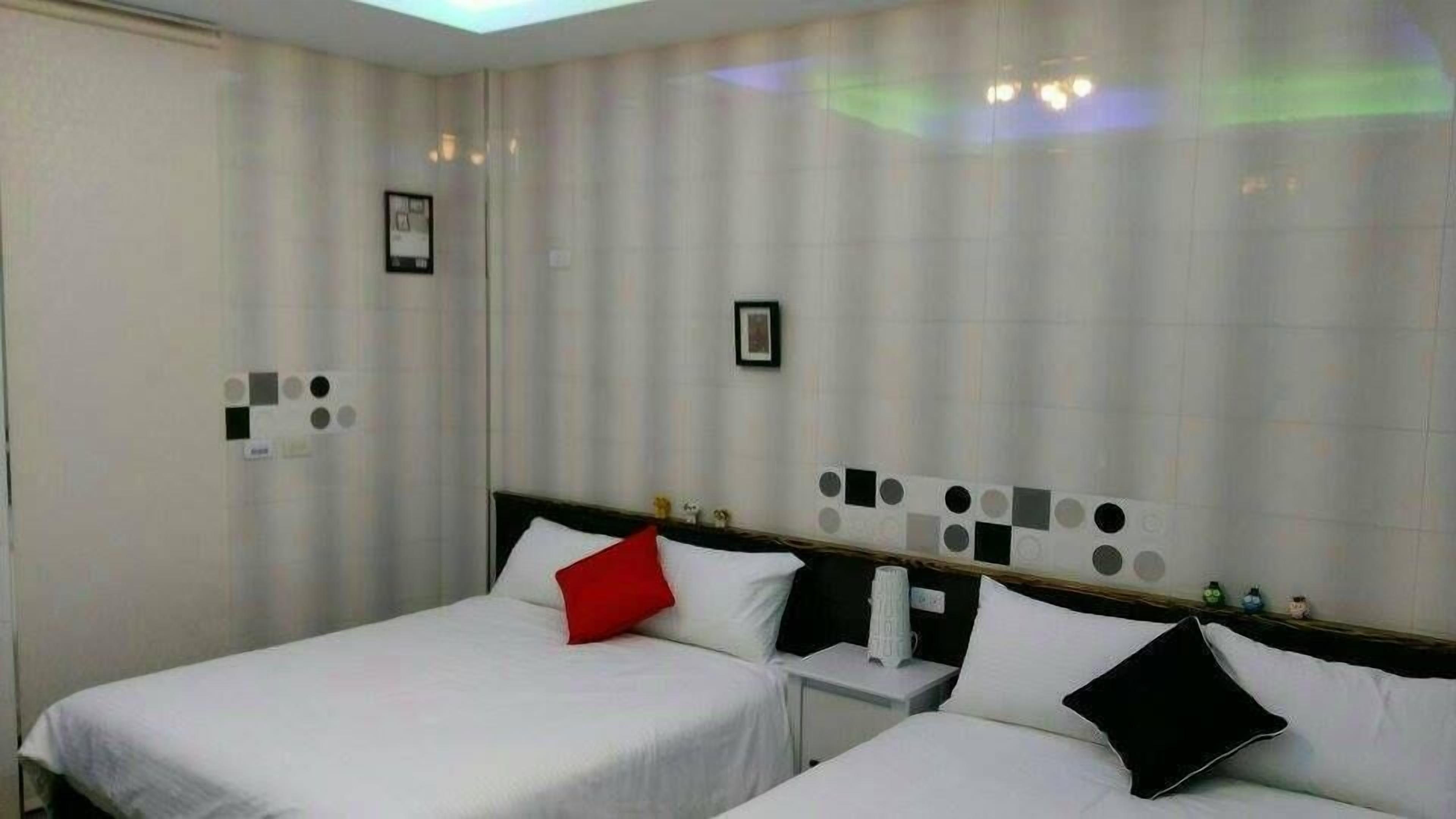 Ein Hotelzimmer mit zwei Betten, einem Nachttisch und einer Wand mit kreis- und quadratischen Mustern.