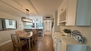 A modern kitchen with wooden flooring, white cabinetry, and a central island. - Renovated, Gulf View Unit, Overlooking the Pool and Beautiful Courtyard (Sarasota)