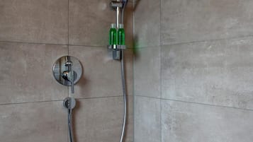 A shower with a handheld showerhead and a wall-mounted faucet.