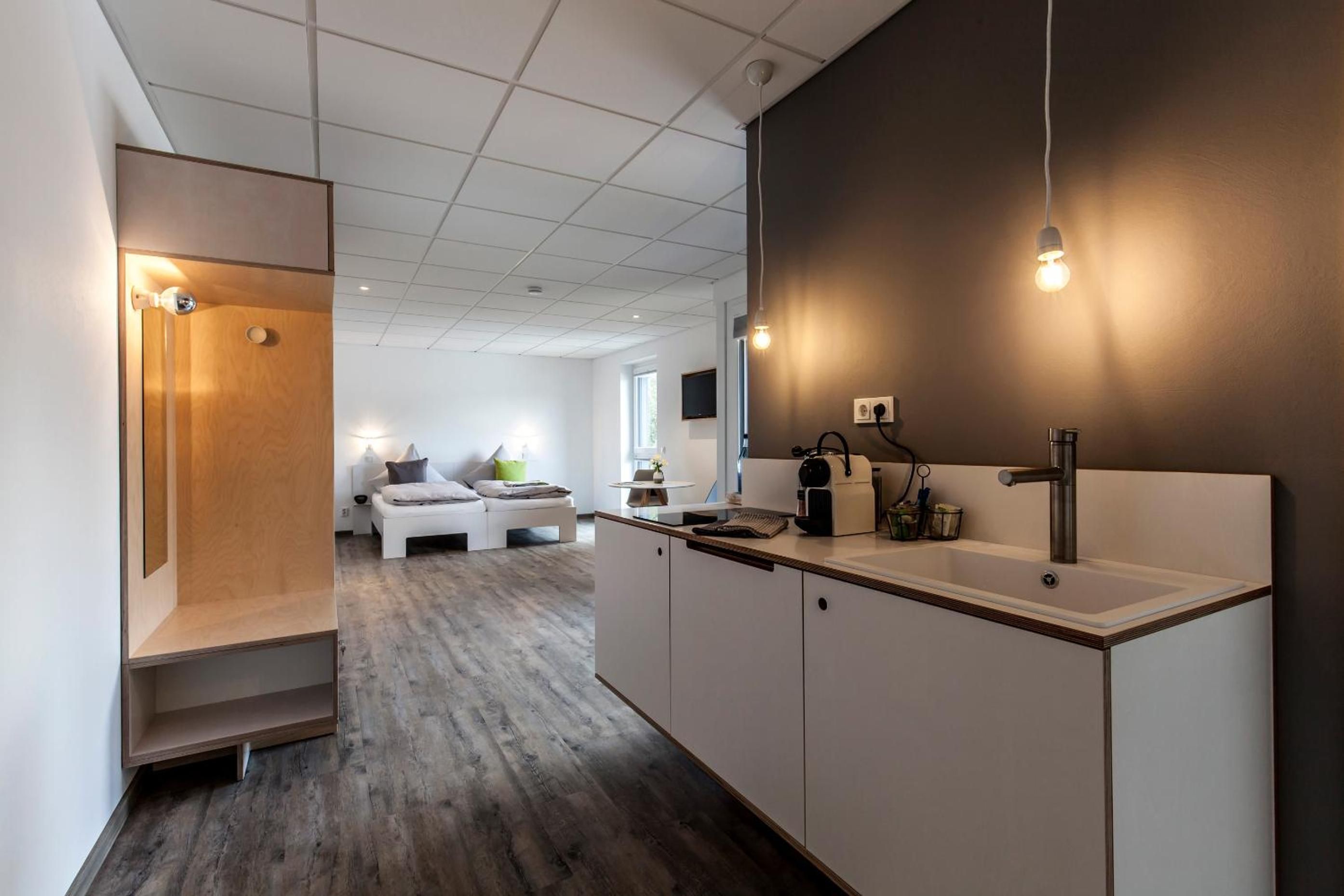 A modern kitchen with a built-in sink, a coffee machine, and a dining area with a white table and chairs.